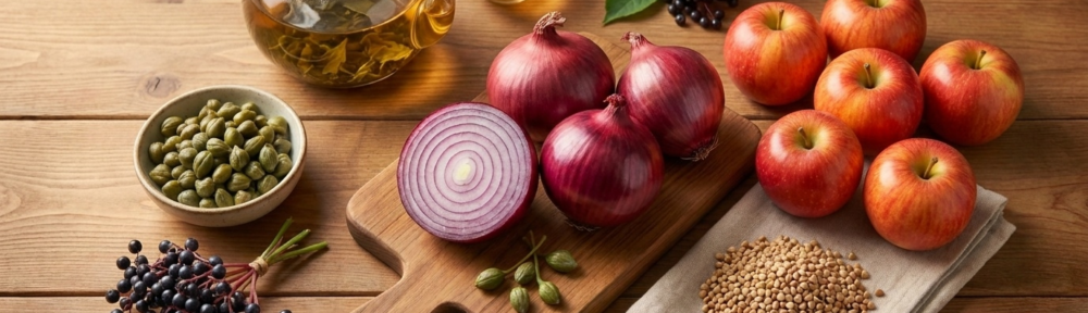 Photographie culinaire hyperréaliste des sources alimentaires naturelles riches en quercétine : oignon rouge coupé révélant ses couches violacées, pommes rouges, câpres, thé vert, sarrasin et baies sauvages.