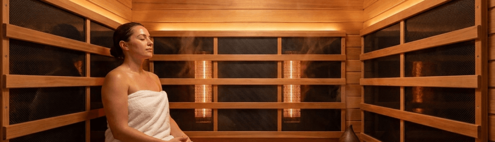 Photographie hyperréaliste de l'intérieur d'un sauna infrarouge moderne en bois de cèdre, avec panneaux chauffants infrarouges intégrés et personne détendue assise profitant d'une séance bien-être.
